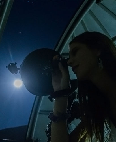 mujer observando las estrellas en un observatorio