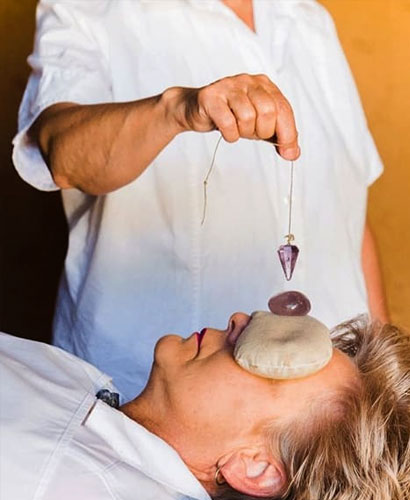 mujer dando terapia con pendulo y piedras